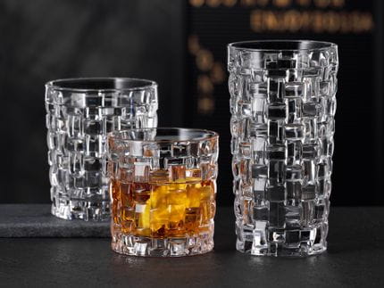 The NACHTMANN Bossa Nova SOF filled with whisky next to the empty Bossa Nova longdrink glass on a black stone sideboard. Behind them the empty Bossa Nova tumbler.<br/>