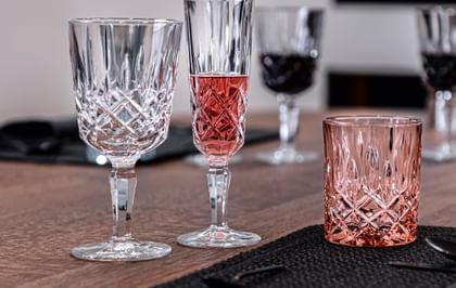 The NACHTMANN Noblesse stemmed cocktail glass, next to the with rosé Champagne filled Champagne glass and the rosé colored tumbler.<br/>