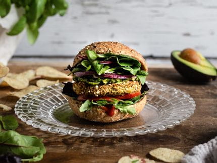 El pequeño plato NACHTMANN Bossa Nova con una sabrosa hamburguesa sobre una mesa, rodeado de hojas de ensalada, patatas fritas, albahaca en una maceta y un aguacate.<br/>